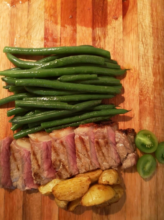 Sliced medium-rare sirloin with green beans and roasted baby potatoes