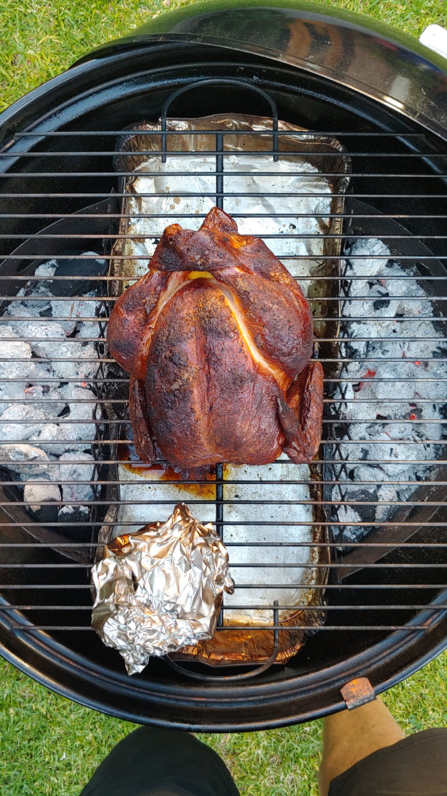 A golden smoked whole chicken on the Weber grid