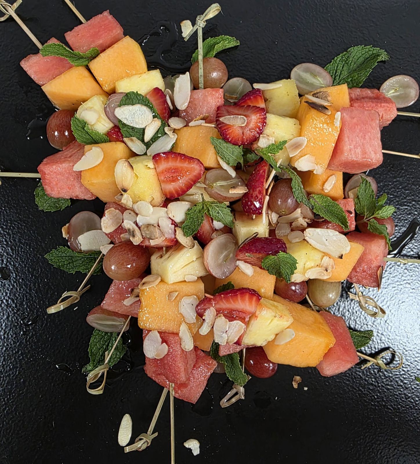 Fruit skewers of melon, strawberry and grapes with toasted almonds
