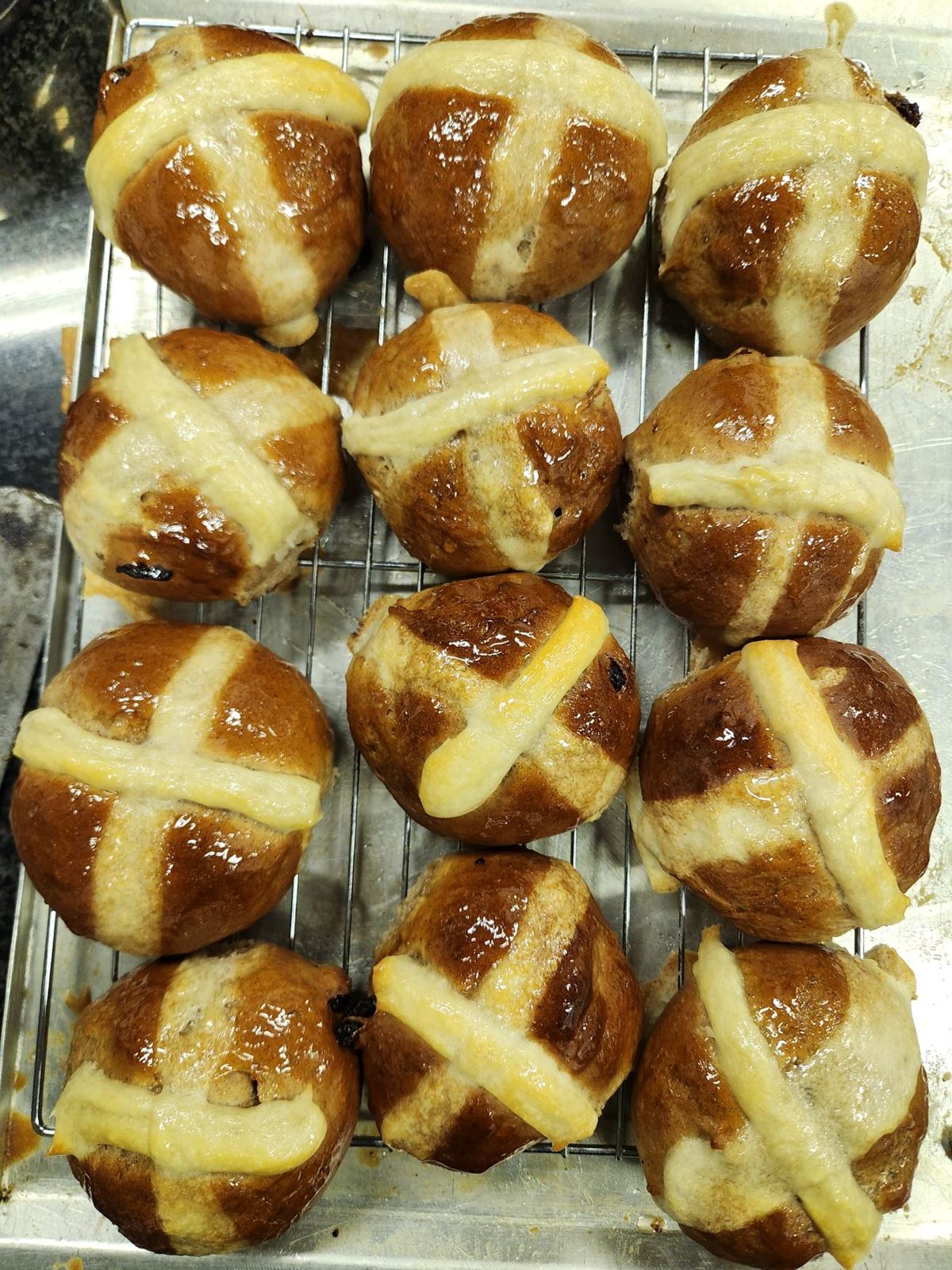 Glazed hot cross buns cooling on a wire rack