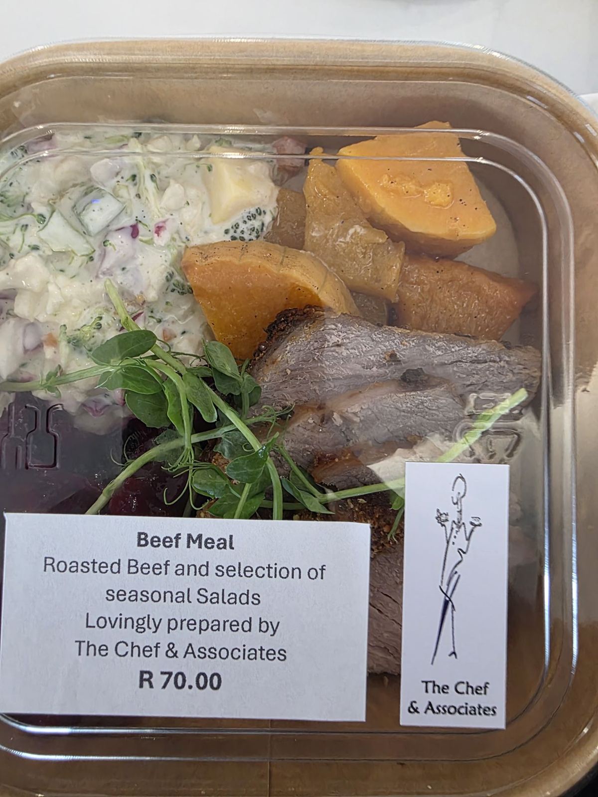 A packed roast beef meal with salads and a branded label