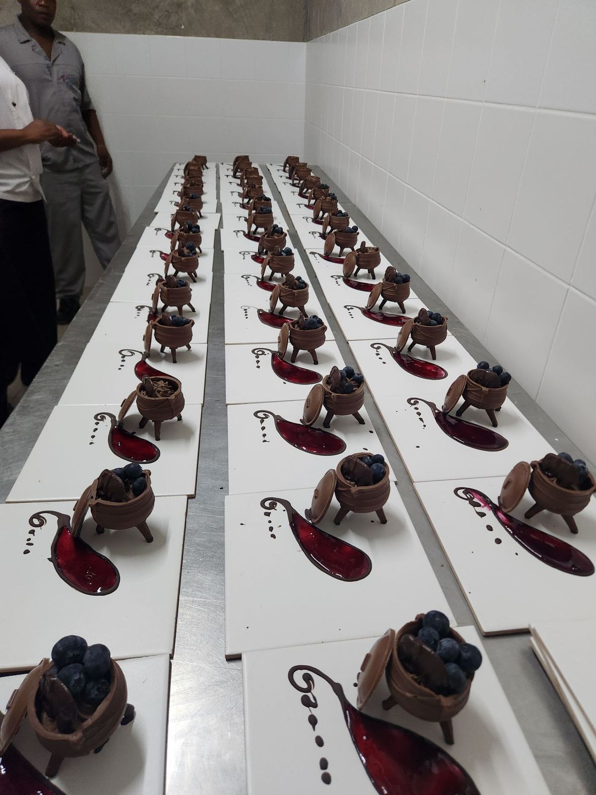 Rows of plated chocolate desserts with berries ready for service