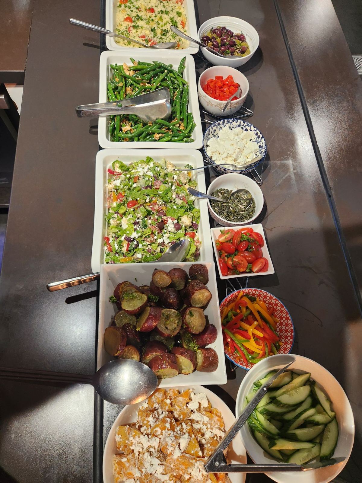A long buffet of salads in white dishes