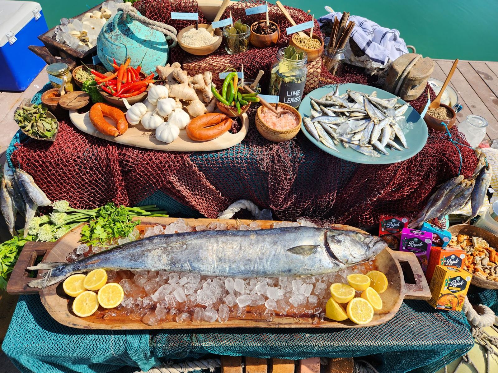 A seafood display with a whole fish on ice, lemons, fresh sardines and spices